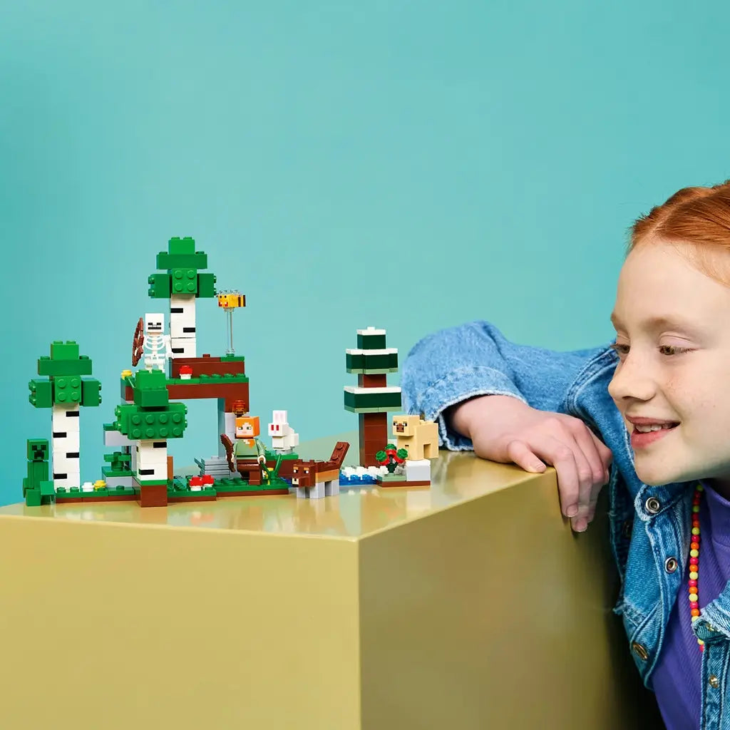 LEGO Minecraft First Night Adventure build uses green, white and brown bricks for a forest shelter with characters and animals, displayed beside a smiling child.