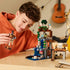 LEGO Minecraft Ghast Station in gray, brown, green and blue bricks stands on a wooden table as a smiling child plays with a suspended ghast and character figure.