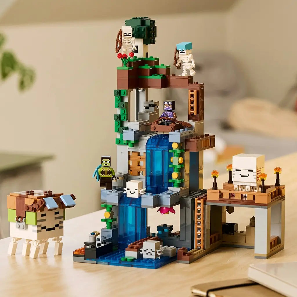 LEGO Minecraft Ghast Station set in gray, brown, green and blue bricks displays a tall waterfall structure, ghasts, skeletons and minifigures on a wooden table.