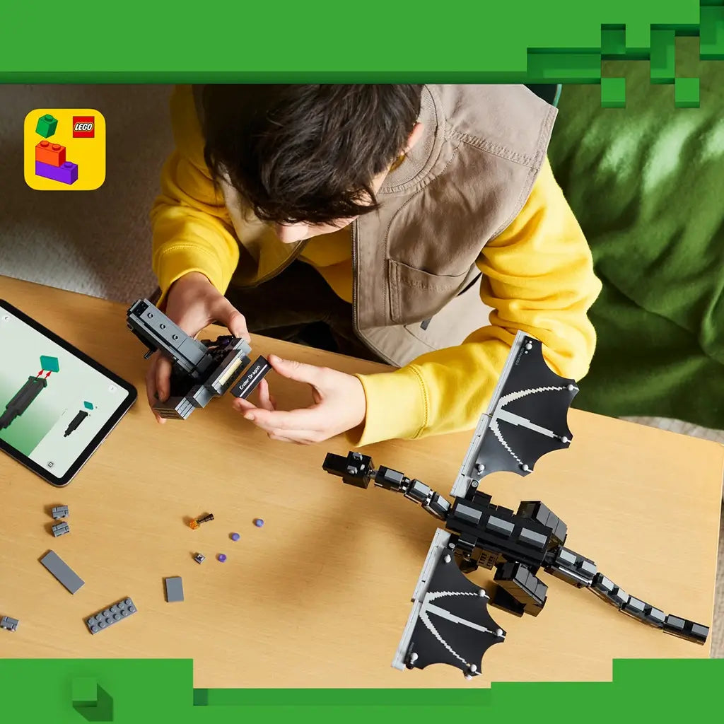 LEGO Minecraft The Ender Dragon build in black and gray bricks lies on a table as a child assembles its display stand beside loose pieces and digital instructions.