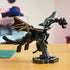 LEGO Minecraft The Ender Dragon model in black and gray bricks spreads articulated wings above a dark display stand on a tabletop, with a softly blurred room behind.