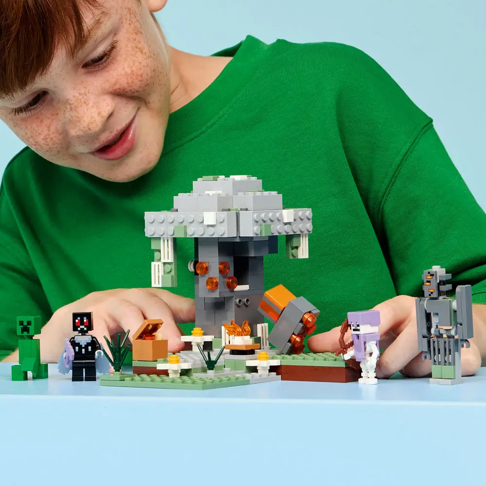 LEGO Minecraft The Pale Garden building scene shows a young builder playing with the completed stone structure while positioning hostile mob figures and accessories around the garden base.