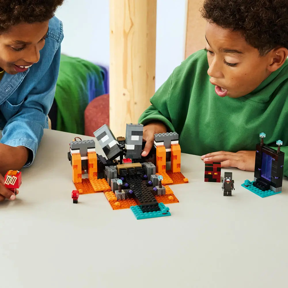 LEGO Minecraft Wither Battle lifestyle builder scene, colorful pixel-style plastic bricks scattered across a table, children actively constructing the fortress and characters together in a bright indoor play environment.