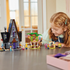 LEGO Despicable Me 4 playset in gray, green and yellow plastic bricks sits on a table as a child plays with Gru’s mansion, treehouse, zip line and Minion figures.