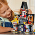 LEGO Despicable Me 4 mansion in gray, black and bright plastic bricks is assembled by a child, with Minions, laboratory equipment and character figures on a table.