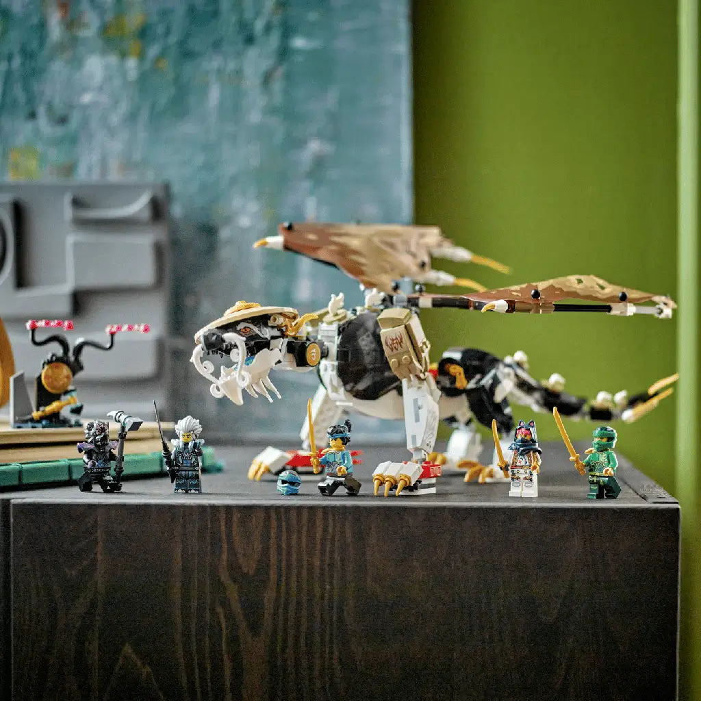 LEGO NINJAGO dragon set in white, black, tan and gold plastic features a winged Master Dragon with six minifigures posed on a dark wood table in a green room.