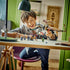 LEGO NINJAGO dragon set in white, black, tan and gold plastic is held by a smiling child, with colorful ninja minifigures arranged across a desk in a green room.
