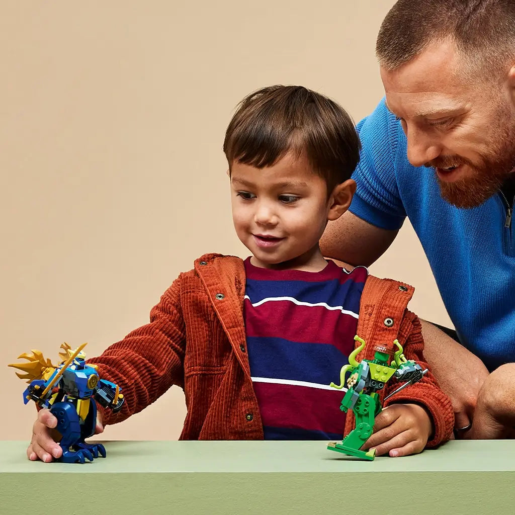 LEGO NINJAGO mech toy in blue and green plastic, small robot figures with movable limbs and weapons, action play scene with a child and adult in a simple indoor setting.
