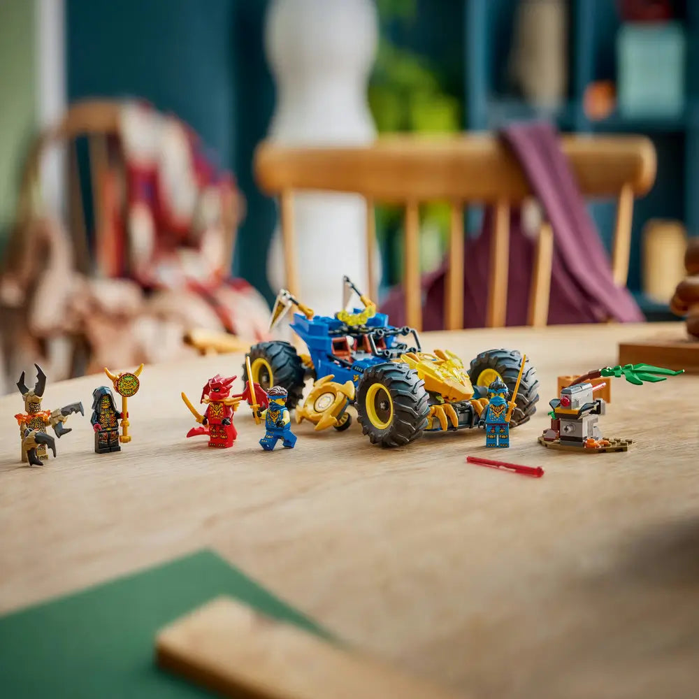 LEGO NINJAGO playset arranged on a tabletop with a completed blue and gold vehicle, textured black tires, and ninja minifigures standing nearby, staged to show finished build details and display-ready play scenes.
