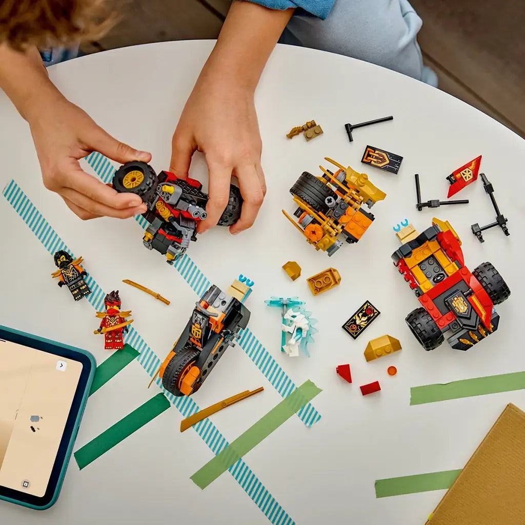LEGO NINJAGO vehicle parts in red, black and gold plastic cover a white tabletop as a child assembles the buggy beside a motorcycle, figures and digital instructions.