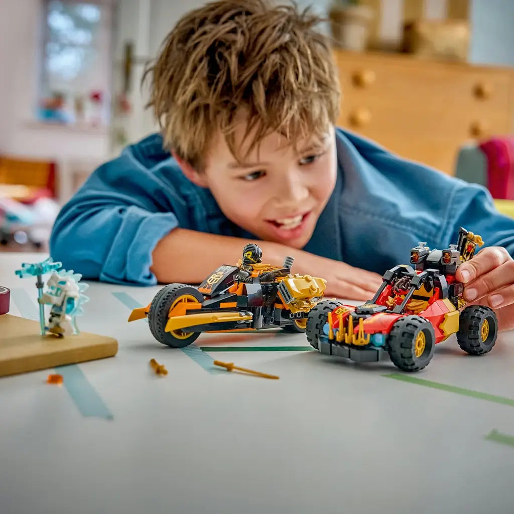LEGO NINJAGO vehicle set in red, black and gold plastic is played with by a smiling child, with Kai's buggy, Cole's motorcycle and an icy figure on a white table.