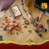 LEGO NINJAGO Land Bounty building scene shows a red and black six-wheel chassis, red ship, minifigures and loose plastic pieces beside digital instructions on a wood table.