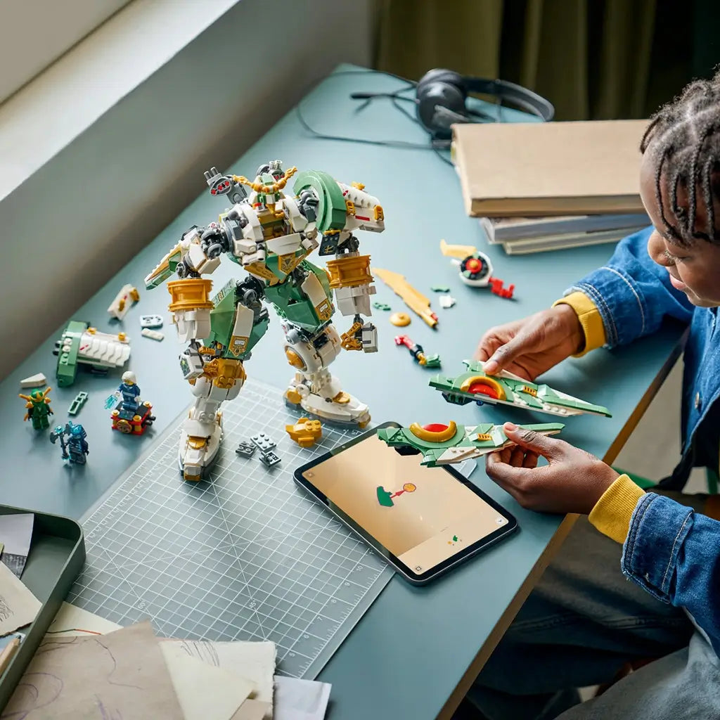 LEGO NINJAGO Titan Mech build in green and white plastic pieces, large robot structure with movable limbs, construction toy in progress on a desk with scattered parts and digital instructions.