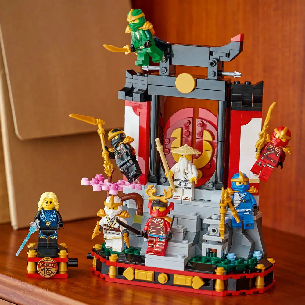 LEGO NINJAGO Legacy ninja temple display fully assembled in red, black, gray, and gold plastic, presented on a tabletop with multiple ninja minifigures posed around the shrine in a home setting.