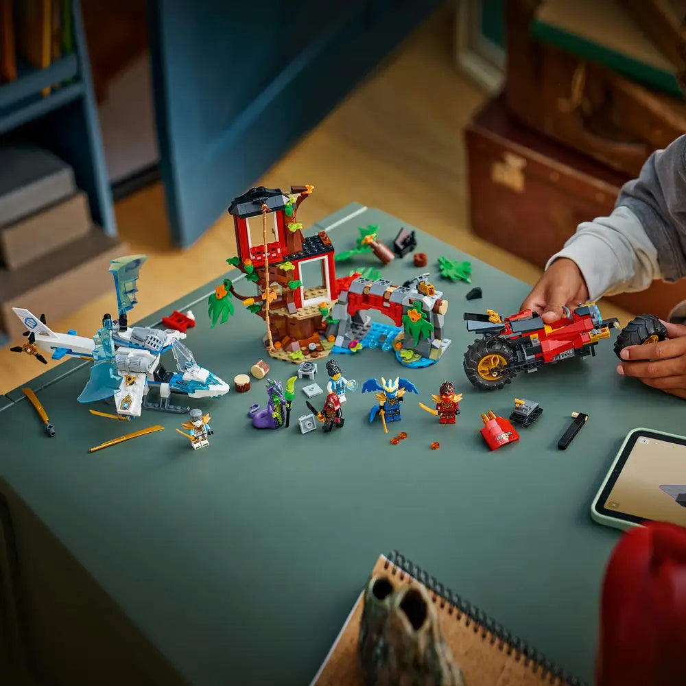 LEGO NINJAGO Ninja Vehicle Tree House Battle lifestyle build scene showing the set mid-assembly on a tabletop, with loose bricks, vehicles, minifigures, and accessories arranged for creative construction play.