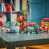 LEGO NINJAGO Dragons Rising Ninja Vehicle Tree House Battle fully assembled in red, brown, green, and gray plastic, displayed on a table with the tree house structure, vehicles, and minifigures arranged to show scale and play options.