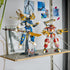LEGO NINJAGO Twin Titan Mechs in red, blue, white and gold plastic stand on a shelf, with the blue mech on a display stand and three minifigures arranged below.
