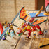LEGO NINJAGO dragon mech in red and gold plastic stands with wide flame-pattern wings beside a black-and-gold mech and four minifigures on a rustic wooden tabletop.
