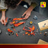 LEGO NINJAGO X-1 Ninja Charger parts in red, black and gold plastic cover a dark tabletop as a builder assembles the car beside a tablet showing digital instructions.