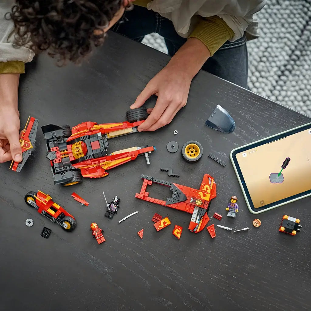 LEGO NINJAGO X-1 Ninja Charger parts in red, black and gold plastic are arranged on a dark table as a builder works beside a tablet displaying digital instructions.