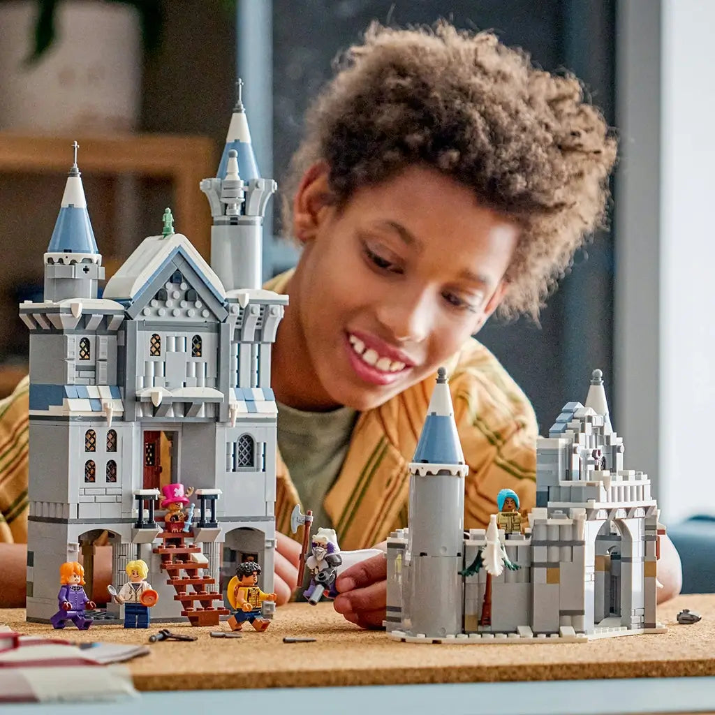 LEGO One Piece Battle at Drum Castle in gray and blue-gray plastic bricks opens into modular sections as a young builder plays with six minifigures at a cork table.
