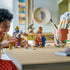 LEGO One Piece Dorry vs. Brogy play scene shows brown and tan brick-built giants facing off with weapons as a young builder moves figures across a tabletop indoors.