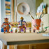 LEGO One Piece Dorry vs. Brogy display features brown and tan brick-built giants with capes, smaller figures, a white lookout structure, and palm tree on a tabletop.