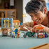 LEGO One Piece playset in gray, tan, orange and green plastic shows a smiling builder moving the motorcycle beside the Recruitment Center, stall and minifigures.