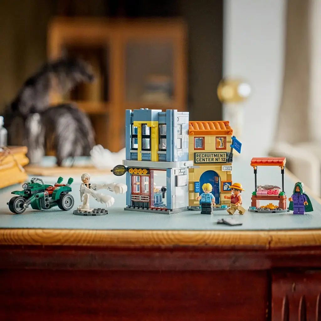 LEGO One Piece display in gray, tan, orange and green plastic features the Recruitment Center, motorcycle, market stall and four minifigures arranged on a tabletop.