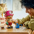 LEGO One Piece Tony Tony Chopper play scene shows a brown brick-built figure with pink hat, blue backpack, medicine accessories, and a smiling builder at a wooden table.