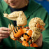 LEGO Pokémon Arcanine build in orange, tan, and black plastic bricks is held by an adult, highlighting the articulated curled tail, striped body, layered mane, and sturdy legs.