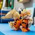 LEGO Pokémon Arcanine display in orange, tan, and black plastic bricks features a seated canine form with layered mane and curled tail, posed on a blue tabletop indoors.