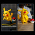 LEGO Pokémon Pikachu collectible display features bright yellow plastic surfaces, a rounded creature shape with movable ears and tail, paired with a Poké Ball and shown in display and play positions indoors.
