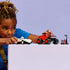 Child assembling LEGO Sonic the Hedgehog Knuckles’ Monster Truck made of red plastic with oversized wheels and a blocky off-road shape, holding pieces at hand scale to show interactive building and creative play.
