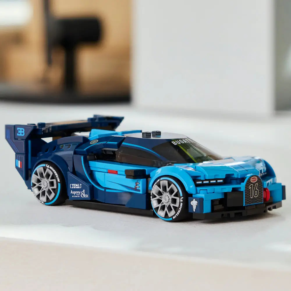 Completed LEGO Bugatti Vision Gran Turismo model car in bright blue plastic with smooth aerodynamic body, low racing stance, silver wheels, and rear wing, positioned for display on a clean tabletop with blurred background.