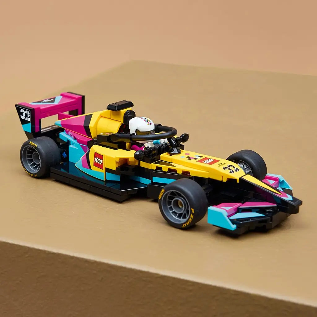 LEGO Speed Champions race car, yellow black pink and teal plastic Formula 1 model with low aerodynamic shape and racing tires, displayed on a tan platform against a soft neutral background.