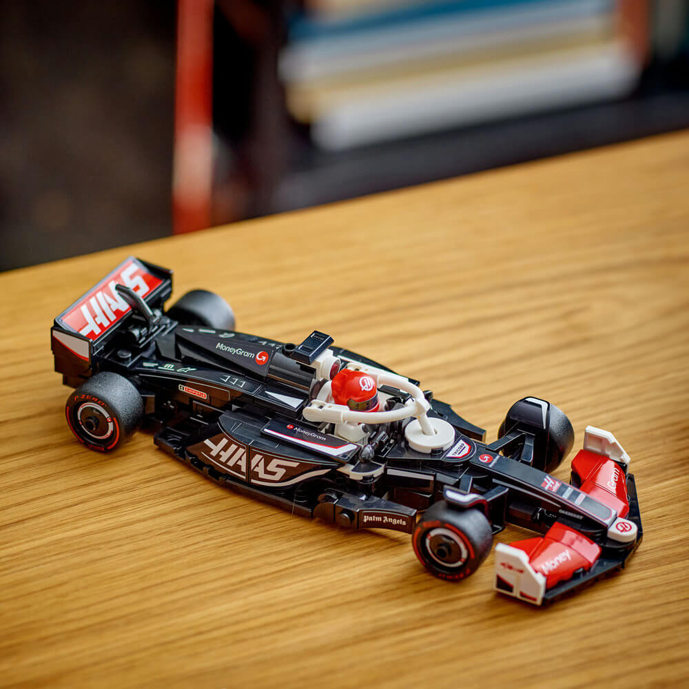 LEGO Speed Champions MoneyGram Haas F1 Team VF-24 black, red and white race car sits on a wooden tabletop, highlighting realistic Formula 1 styling in an indoor display with authentic sponsor graphics.