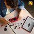 Child assembling the LEGO Ferrari SF90 XX Stradale on a wooden table, showing red and black car components, loose wheels, minifigure parts, and a tablet displaying step-by-step digital building instructions