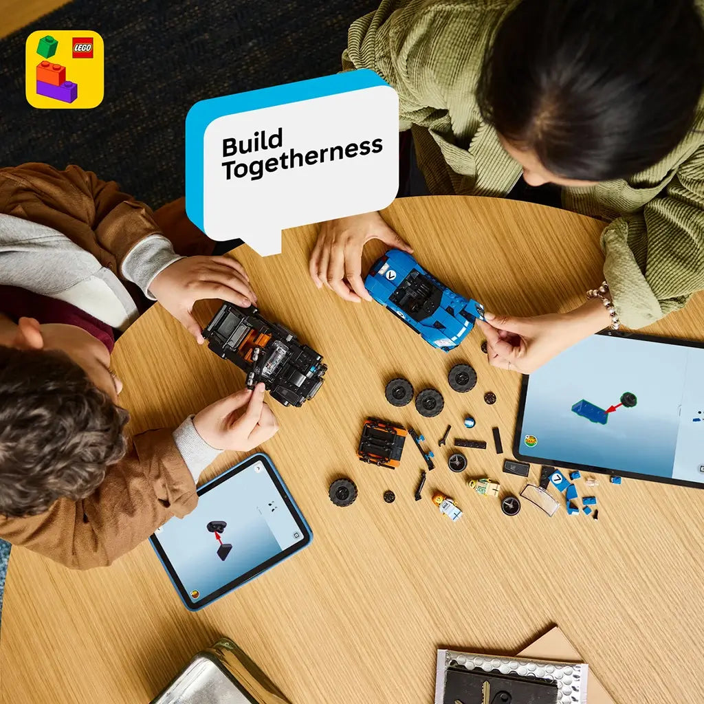 LEGO Speed Champions building set in blue and black plastic is assembled by a child and adult on a wooden table with loose wheels, pieces, minifigures and two tablets.