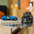 LEGO Speed Champions Jaguar Project 7 in blue and Land Rover Defender in black are displayed as detailed brick-built vehicles on a glass table in a modern indoor setting.