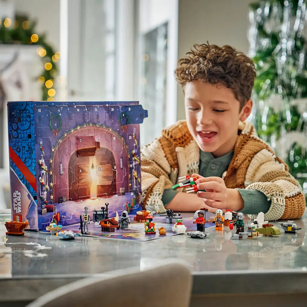 LEGO Star Wars Advent Calendar 2026 play scene shows a child holding a red, green and white mini starship beside minifigures and builds arranged around the open calendar.