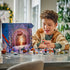 LEGO Star Wars Advent Calendar 2026 play scene shows a child holding a red, green and white mini starship beside minifigures and builds arranged around the open calendar.