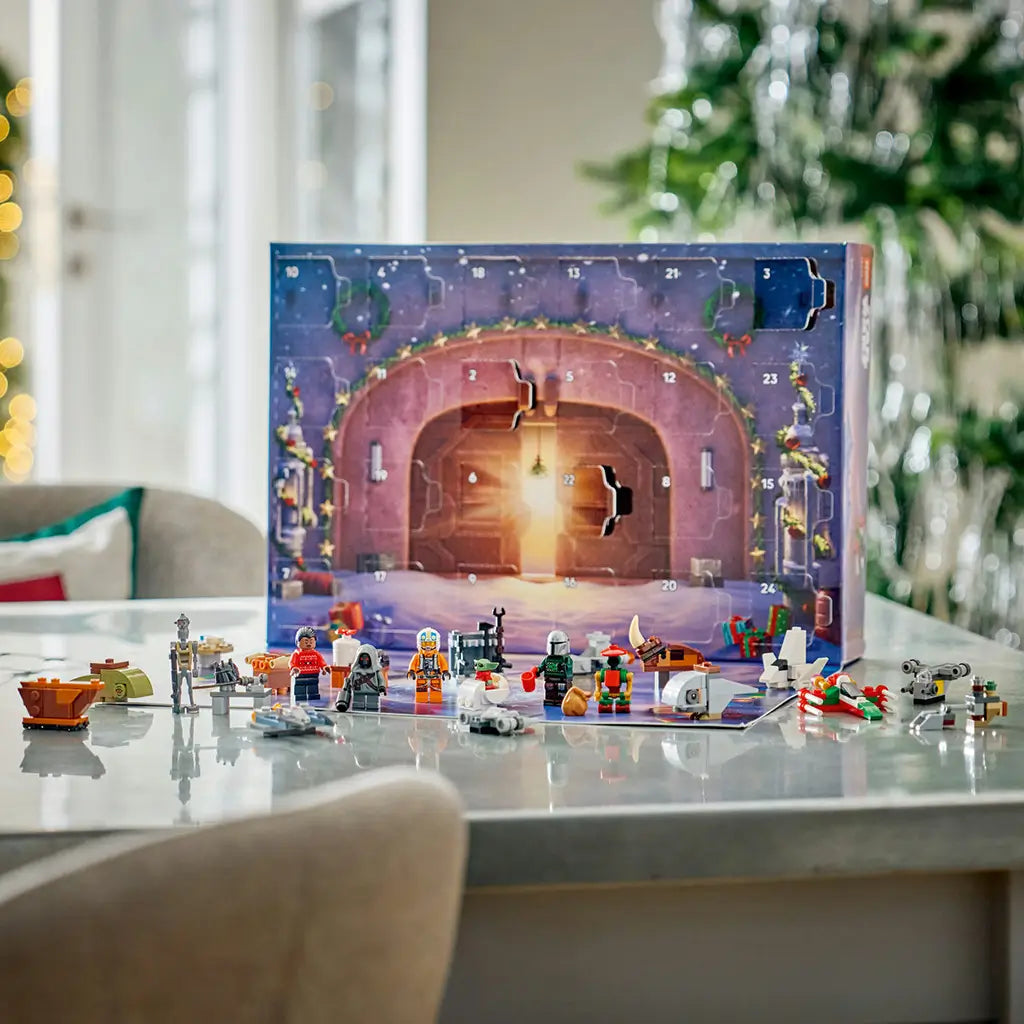 LEGO Star Wars Advent Calendar 2026 display features colorful minifigures, starships, creatures and workshop builds lined up before an open numbered calendar on a table.
