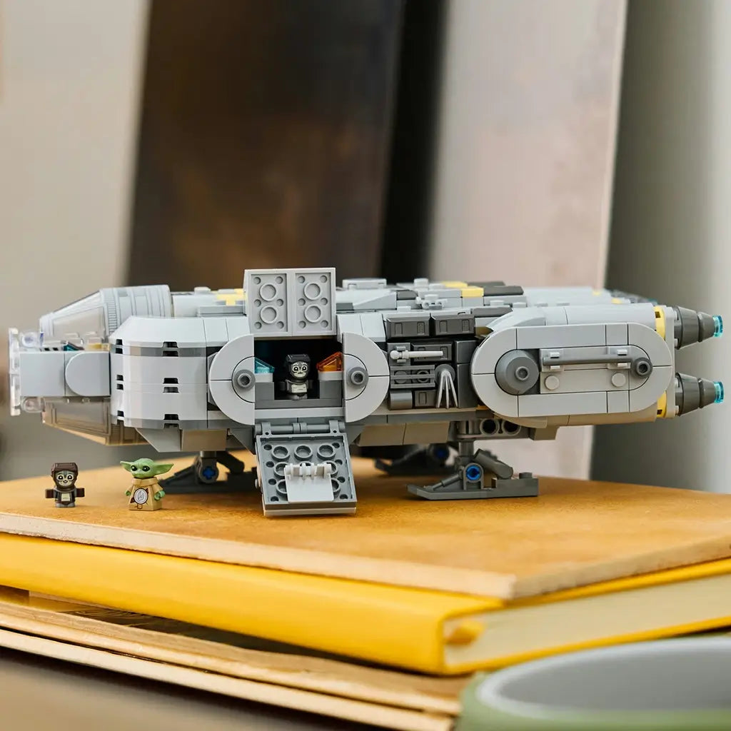 LEGO Star Wars Anzellan Starship display features a gray plastic spacecraft with rounded body panels, opening side compartment and character figures, showcased on stacked books in a home interior.