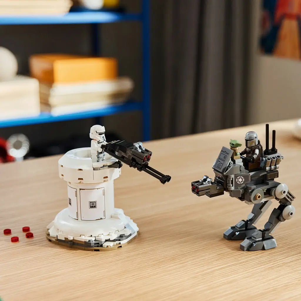 LEGO Star Wars AT-RT Attack display features a gray plastic walker, white cylindrical turret and character minifigures arranged for battle play on a wooden tabletop indoors.