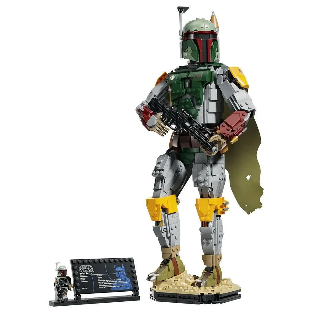 LEGO Star Wars Boba Fett figure in green, gray, red and yellow plastic bricks, posed with black blaster and cape on a tan display base beside a minifigure and plaque.