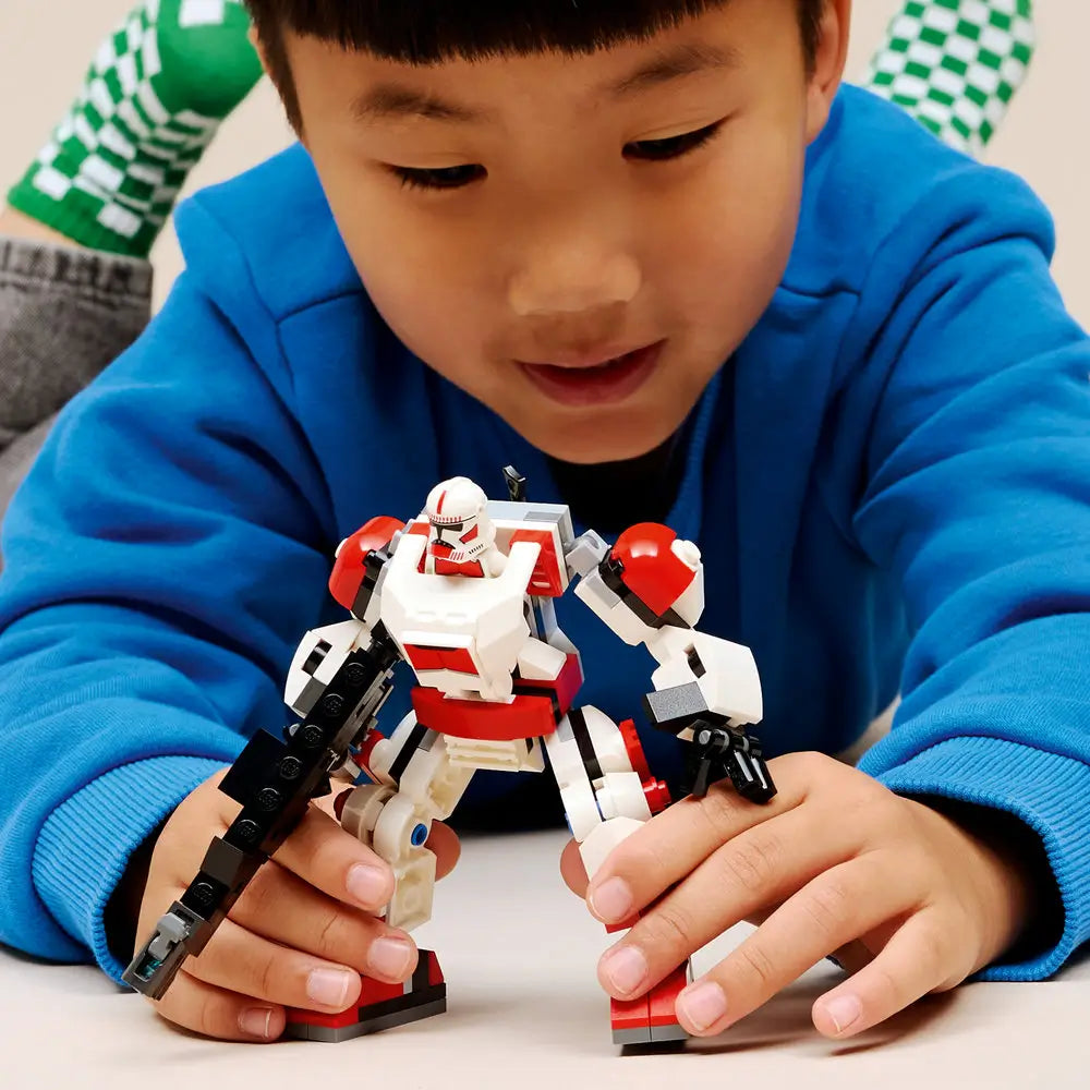 LEGO Star Wars play scene showing a child holding and posing the completed Clone Shock Trooper mech, emphasizing articulated joints, gripping hands, and imaginative role-play in a home environment.