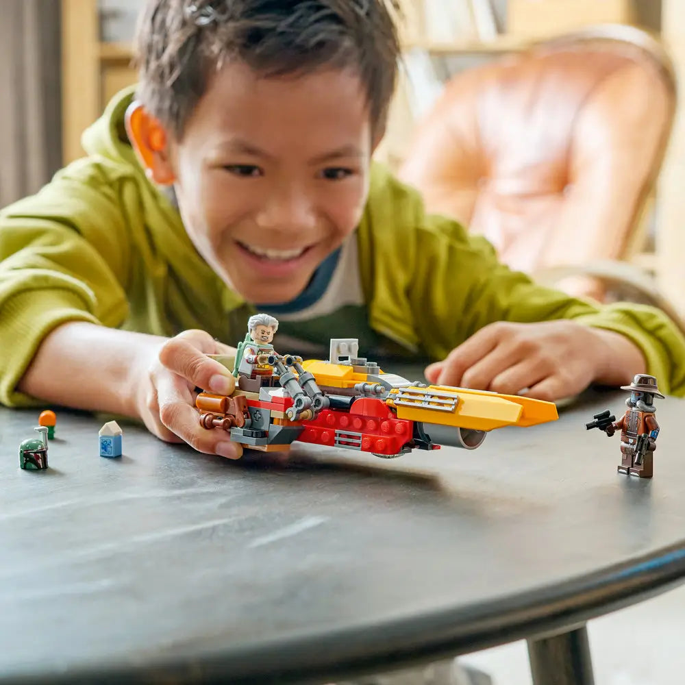 LEGO Star Wars speeder play scene in yellow, red, and gray plastic, held by a smiling child indoors, emphasizing hands-on building, imaginative play, and character interaction.