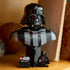 LEGO Star Wars Darth Vader display features glossy black plastic armor panels, a sculpted helmet bust, character plaque and minifigure, presented on a shelf beside books.