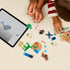 LEGO Star Wars building toy lifestyle image showing a child assembling Grogu’s Homestead pieces on a tabletop, with colorful bricks, nature elements, and digital instructions displayed on a tablet.